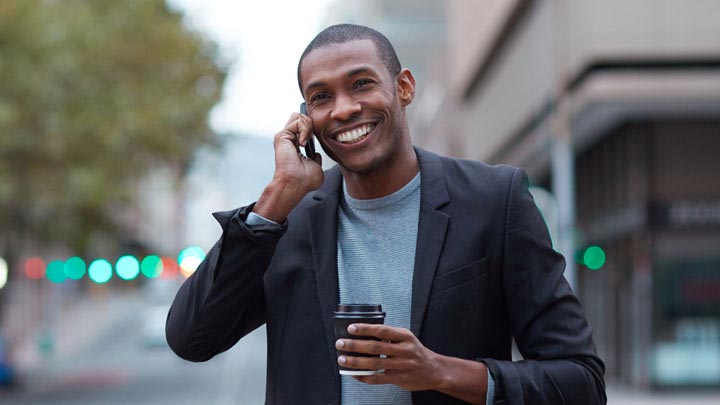 Homem sorrindo ao telefone andando na rua